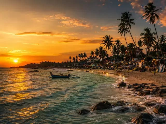 Hikkaduwa beach at sunset with palm trees and a calm shoreline